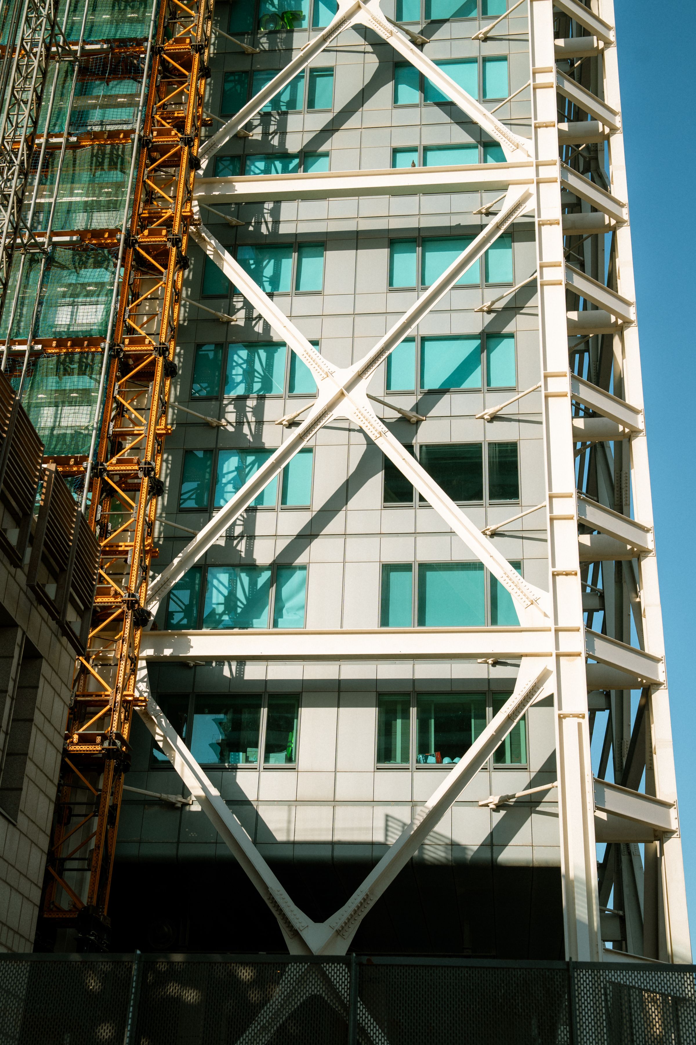 Modern skyscraper with exposed steel bracing against a clear blue sky