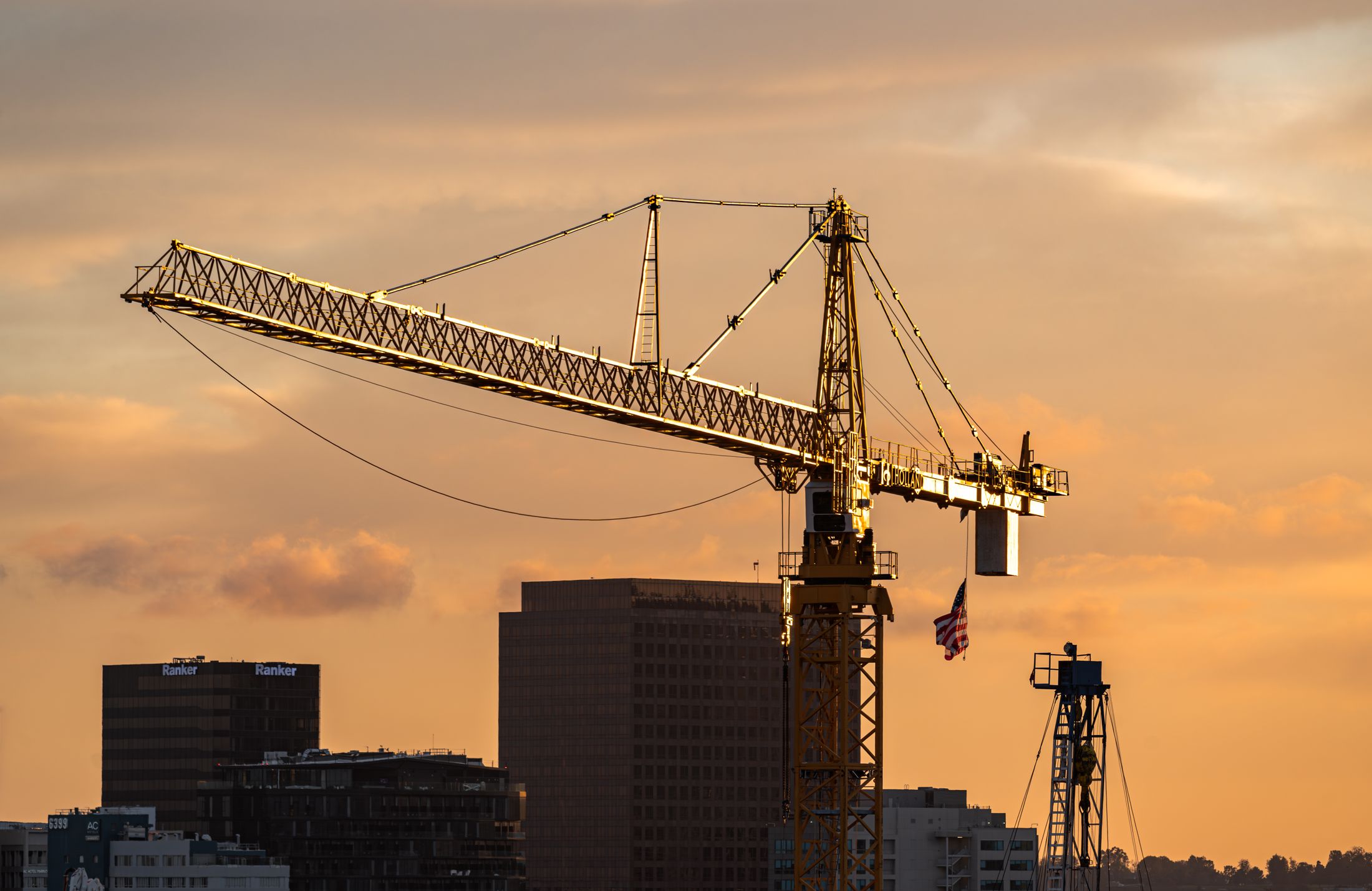 Construction crane silhouetted against a golden sunset sky