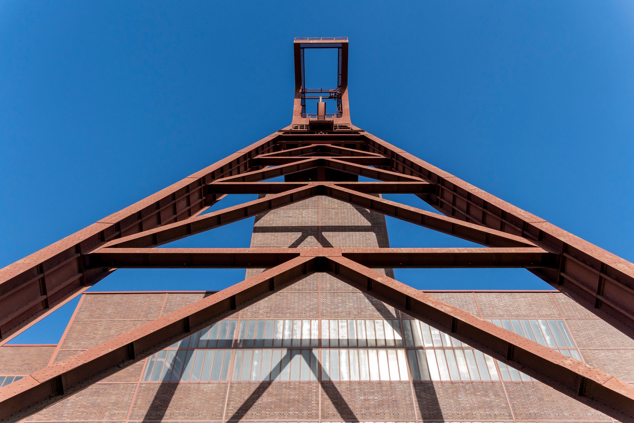 Steel lattice framework viewed from below against a clear blue sky