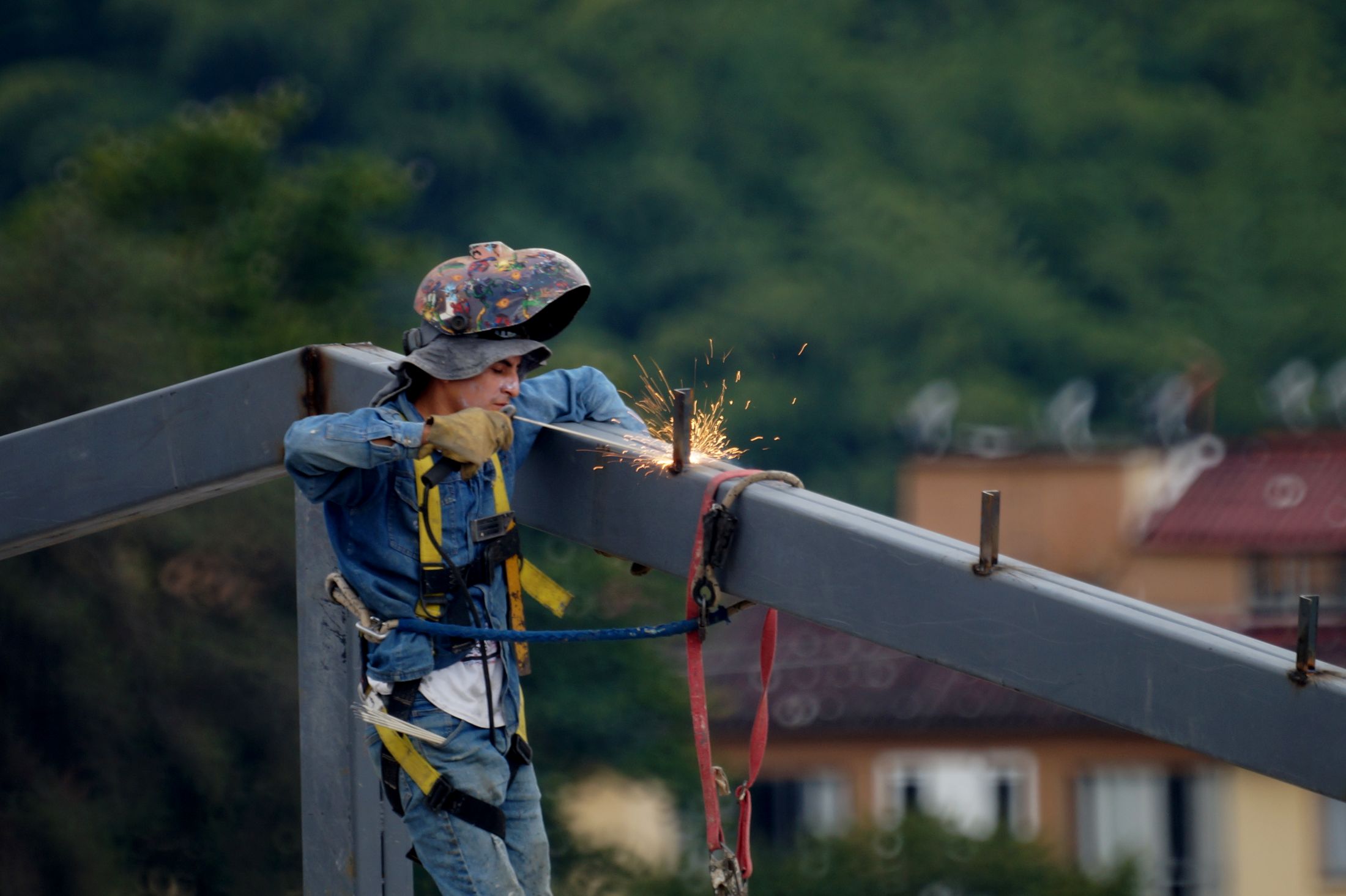 Steel fabricator welding a structural beam at height on a construction site